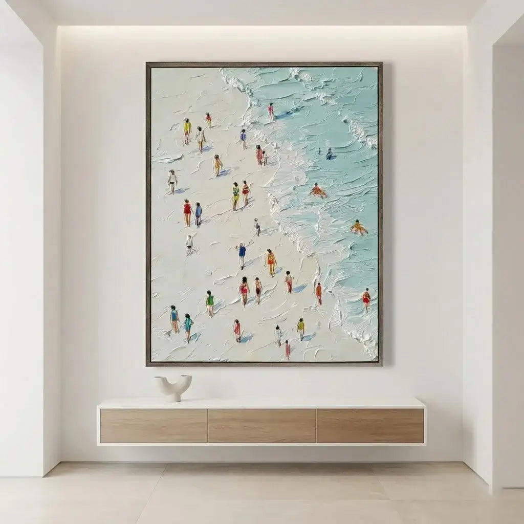 Framed artwork of people on a beach hanging on a wall above a white console table.