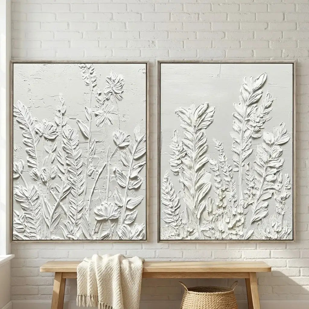 Two framed botanical artworks on a wall with a wooden bench and blanket.