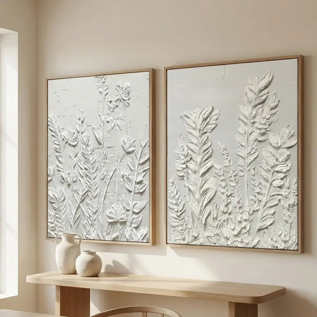 Two framed botanical wall art pieces on a beige wall with a wooden console table below.