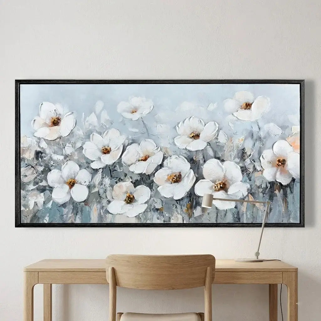 Framed floral artwork on a wall above a wooden desk with a chair.