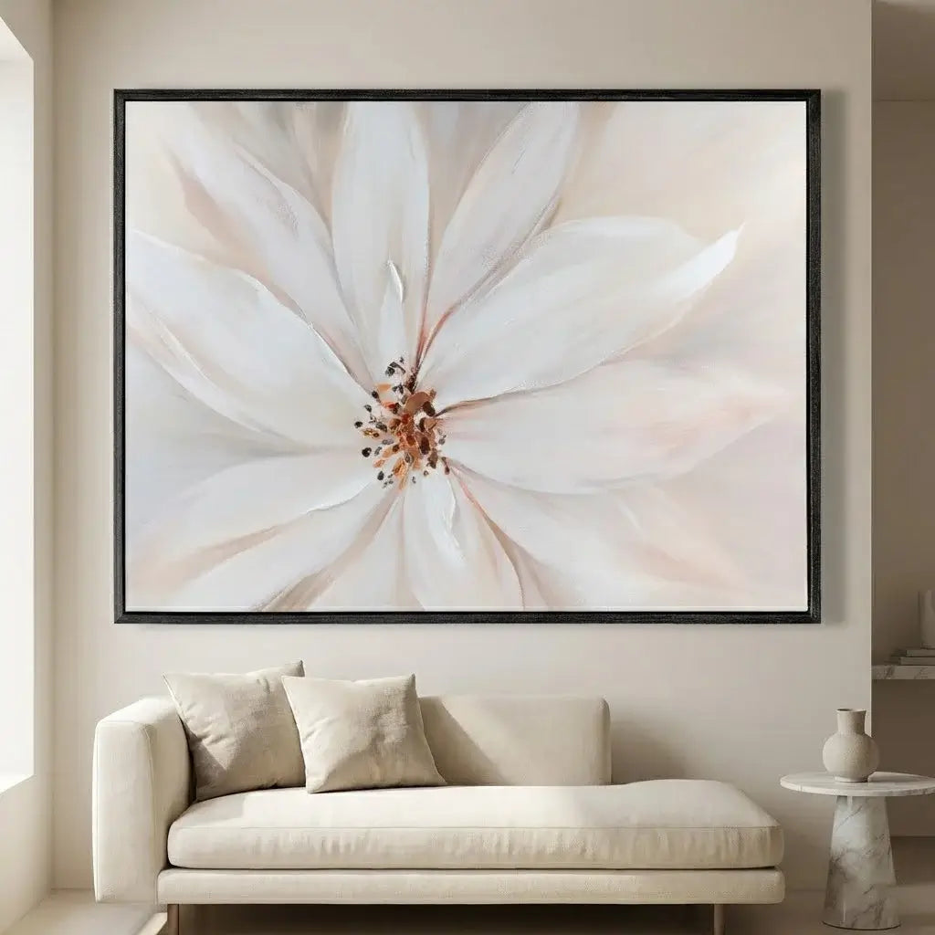 Framed artwork of a white flower on a wall above a beige sofa.