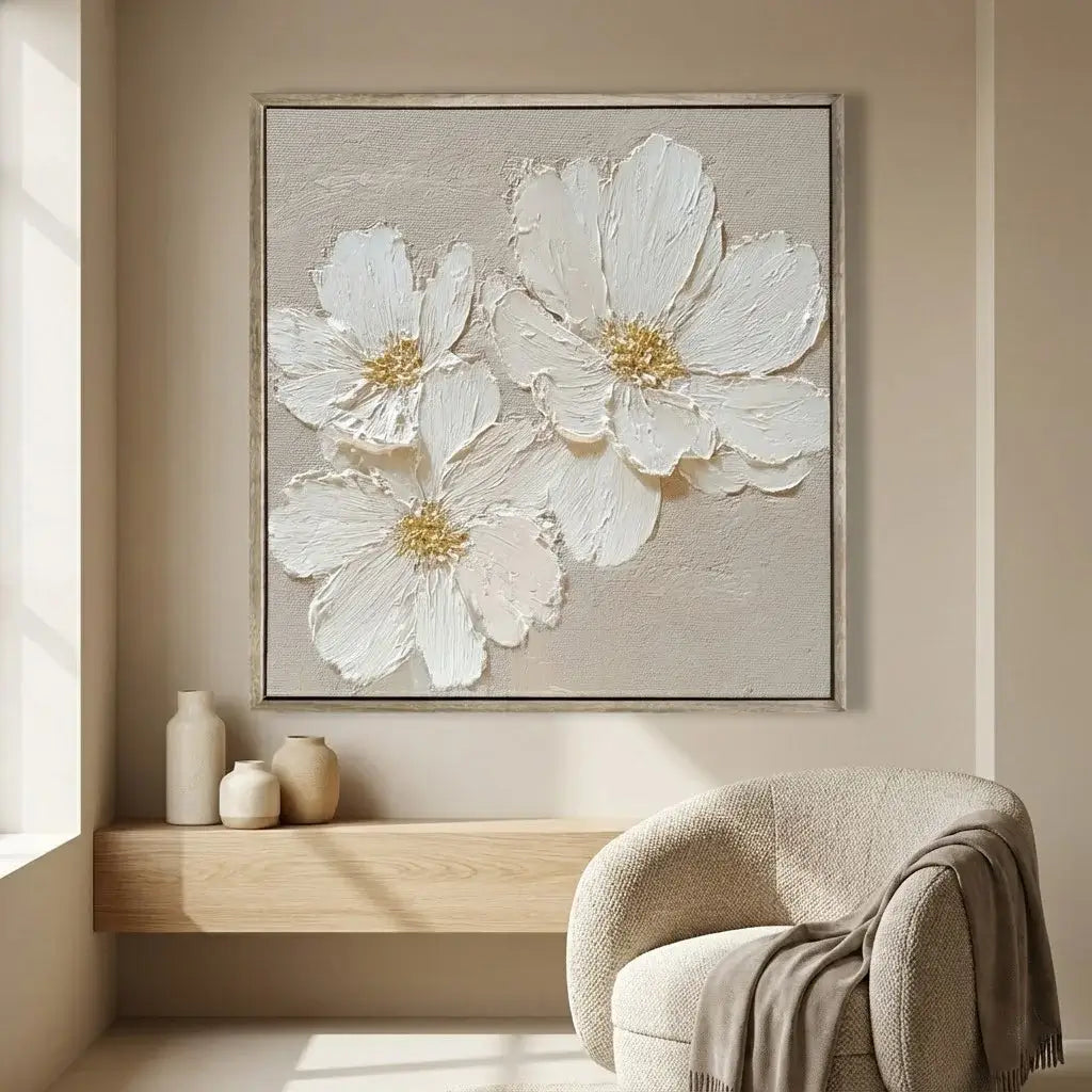 Framed artwork of white flowers on a beige wall above a wooden shelf with decorative items.