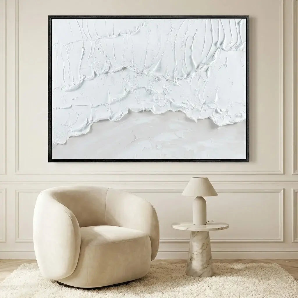 Modern interior with a beige armchair, side table, and abstract painting on a wall.