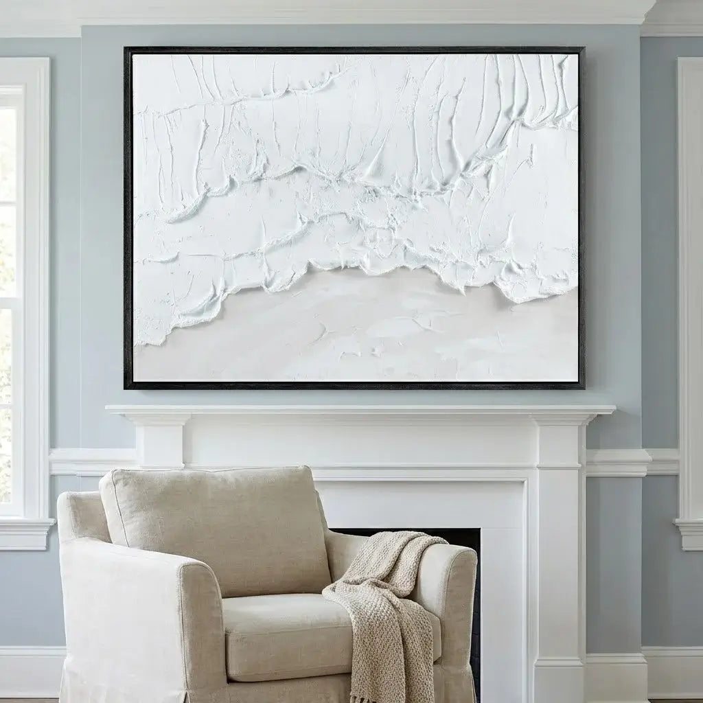 Abstract white artwork on a gray wall above a white fireplace with a beige armchair.