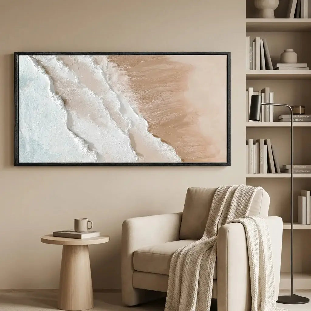 Beige armchair with a blanket, small table, and framed artwork in a room with shelves.