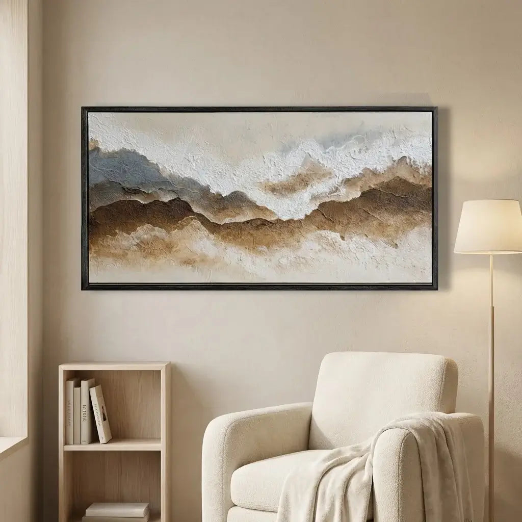 Framed abstract art piece on a wall above a beige armchair in a living room.