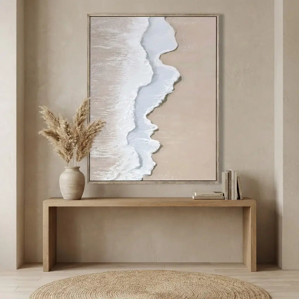 Abstract art piece on a wall above a wooden console table with a vase and books.