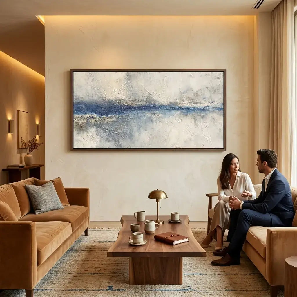 Two people sitting in a modern living room with a large abstract painting on the wall.