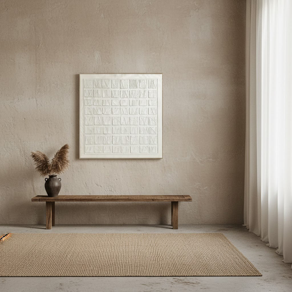 Minimalist interior with a wooden bench, vase with dried plants, and abstract art on a beige wall.