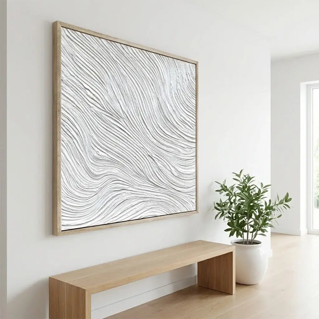 Framed abstract artwork on a wall with a wooden bench and plant in the foreground.