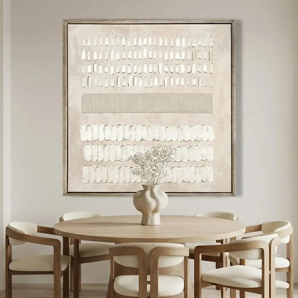 Dining room with round wooden table and chairs, framed abstract art on the wall.