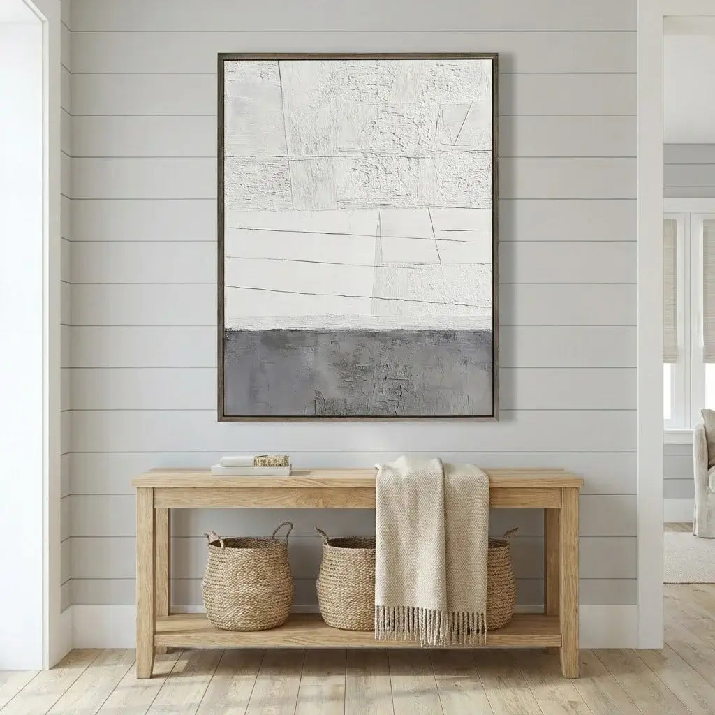 Wooden console table with baskets and a blanket against a wall with abstract art