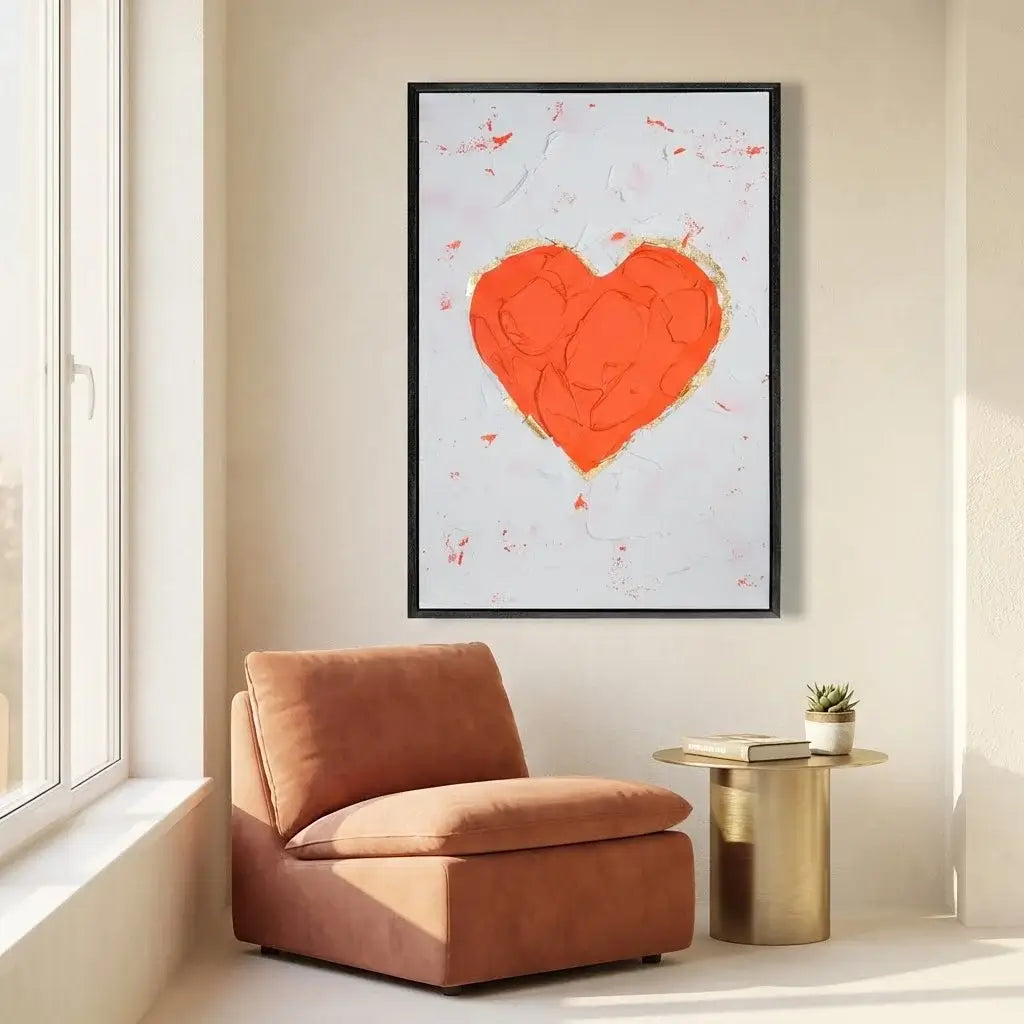 Modern interior with a brown armchair, gold side table, and framed artwork of a red heart on a white background.