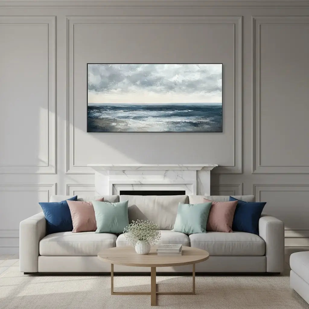 Modern living room with a gray sofa, decorative pillows, and an ocean scene landscape art.