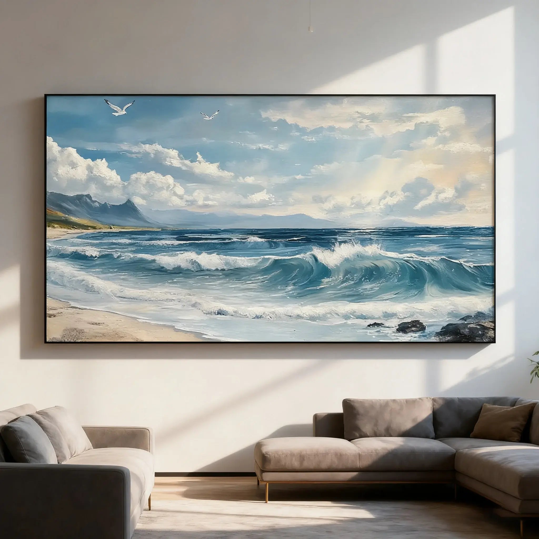 Large oil painting view of a beach with waves and mountains, placed above a sofa in a living room.