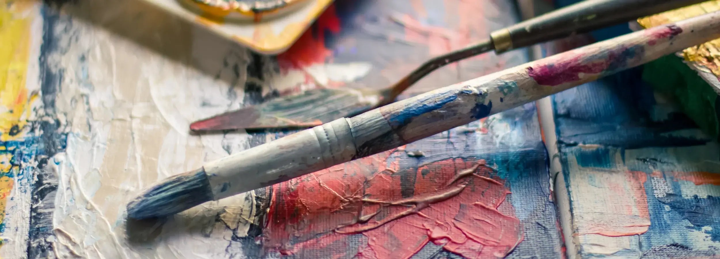 Artistic palette with paintbrushes and colorful paint on a textured surface