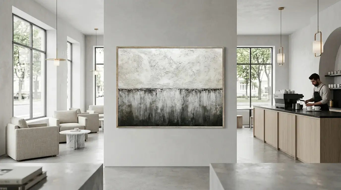 Modern living room with abstract painting on wall and kitchen area.