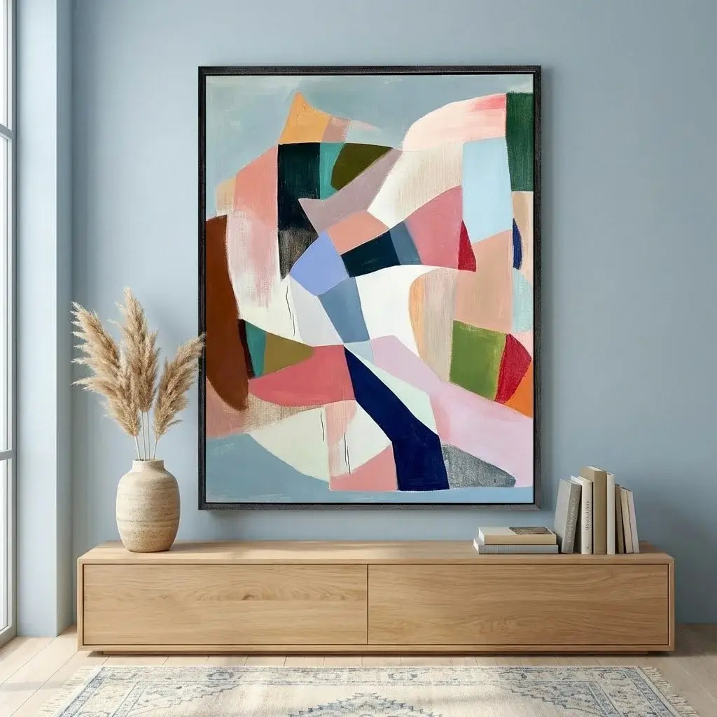 Abstract art piece on a wall above a wooden cabinet with decor items.
