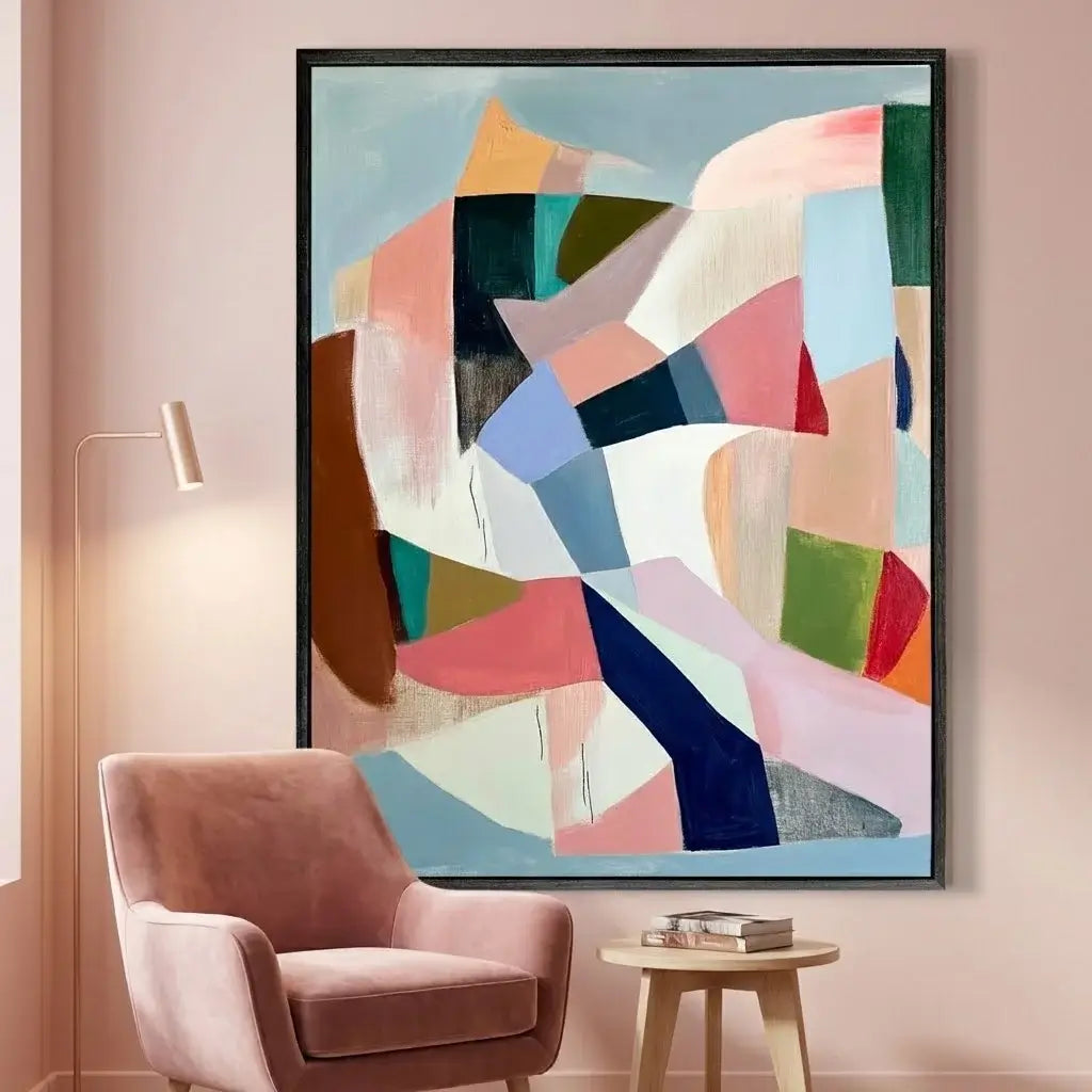 Abstract art piece with colorful geometric shapes on a wall above a pink armchair.