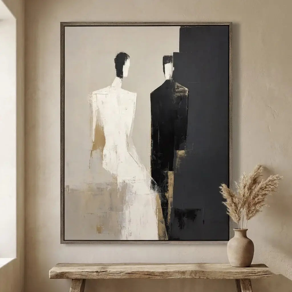 Abstract art piece on a wall with a vase of dried plants below.