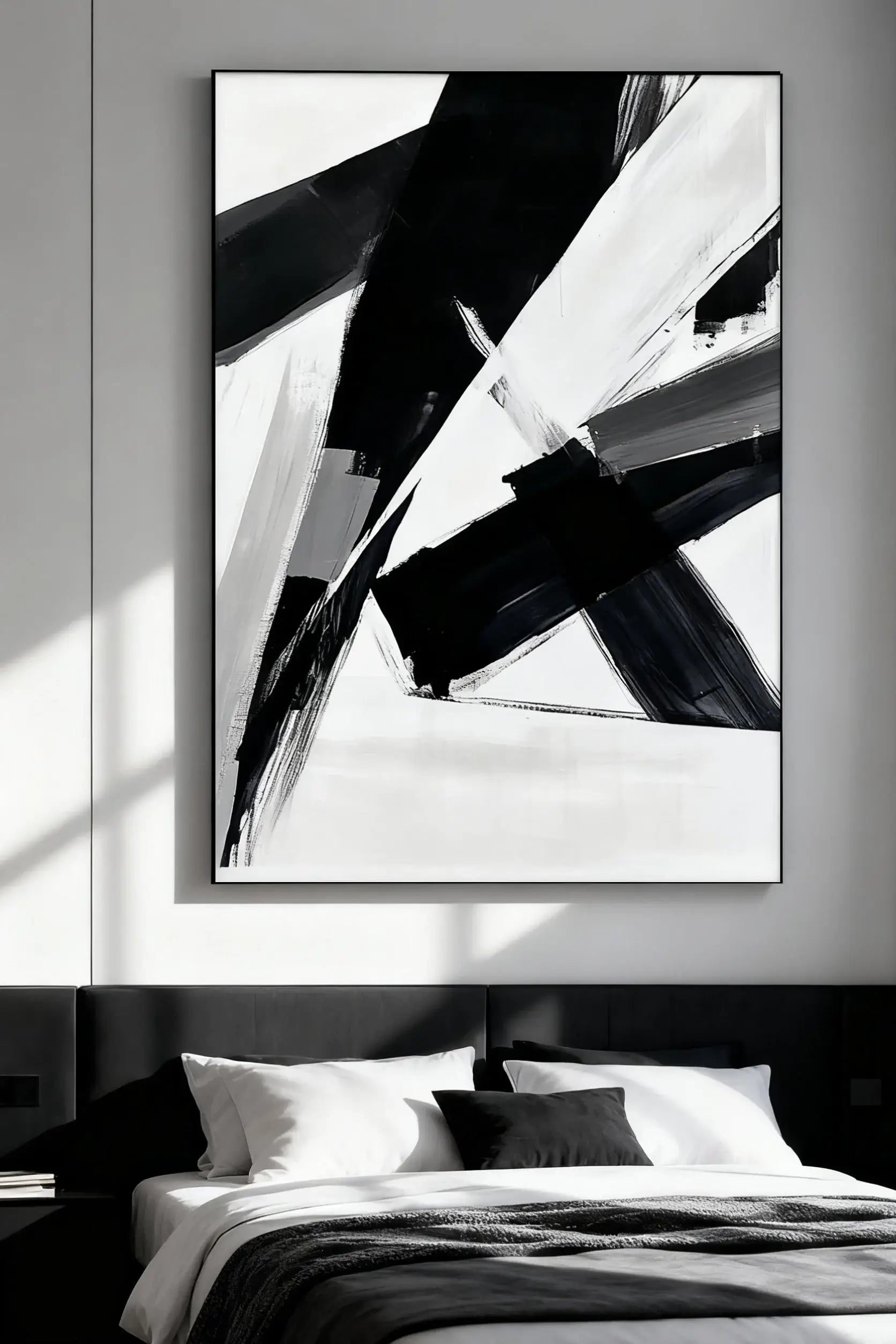 Abstract black and white artwork on a wall above a bed