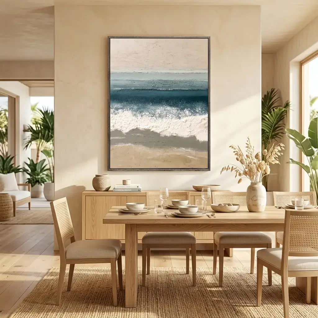 Dining room with a wooden table set for a meal, chairs, and a large framed beach scene on the wall.