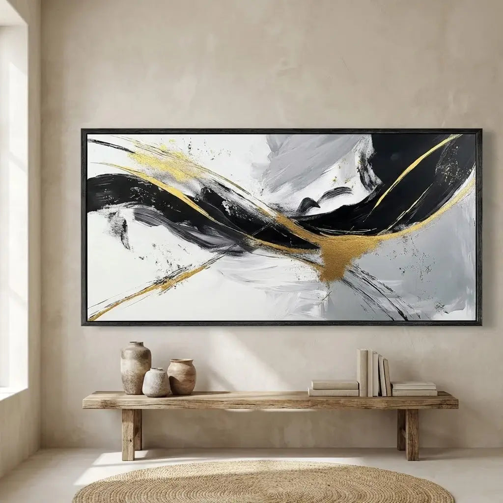Abstract painting with black and gold strokes on a beige wall above a wooden bench.