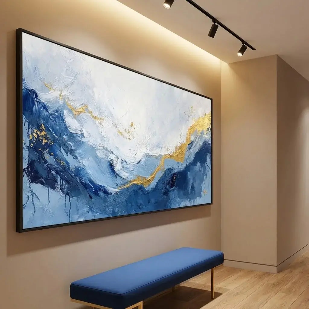 Abstract painting with blue and gold tones on a beige wall above a blue bench.