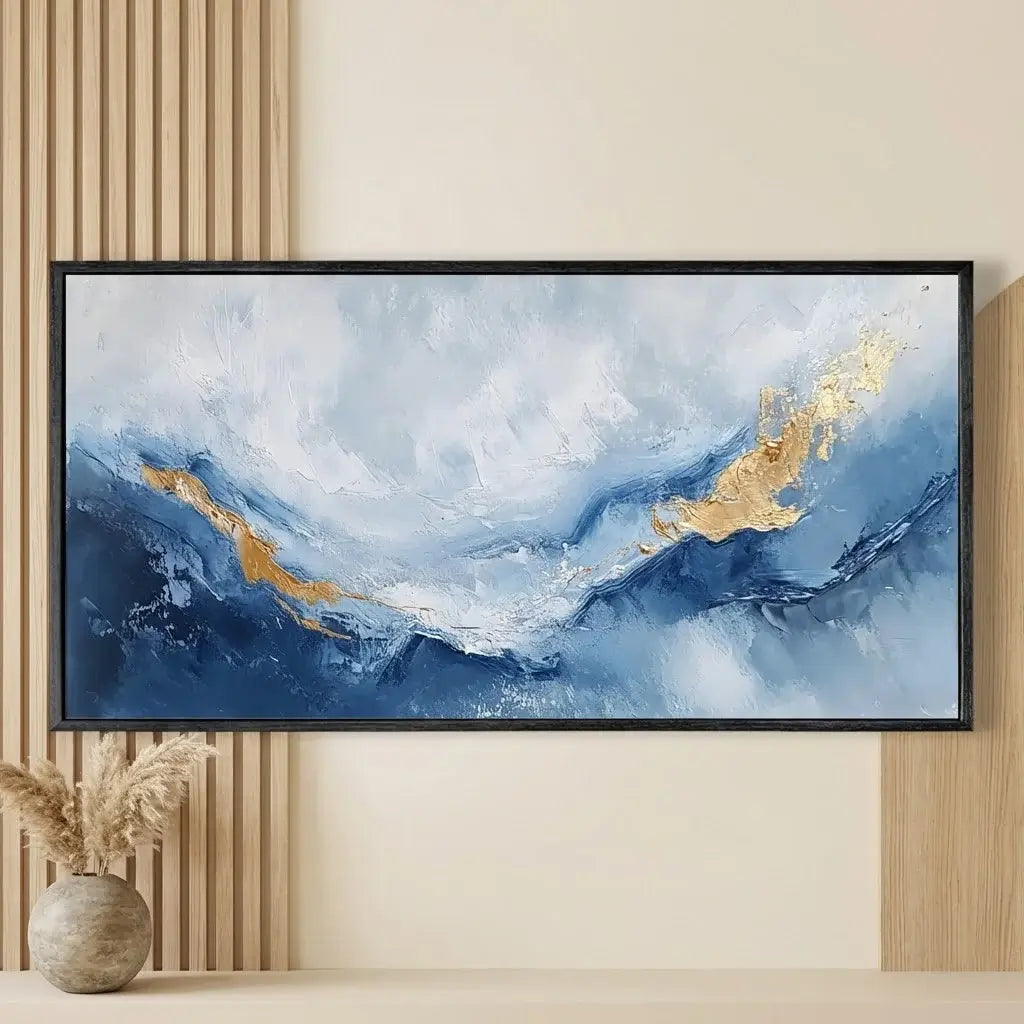 Abstract painting with blue and gold tones in a black frame on a wall.