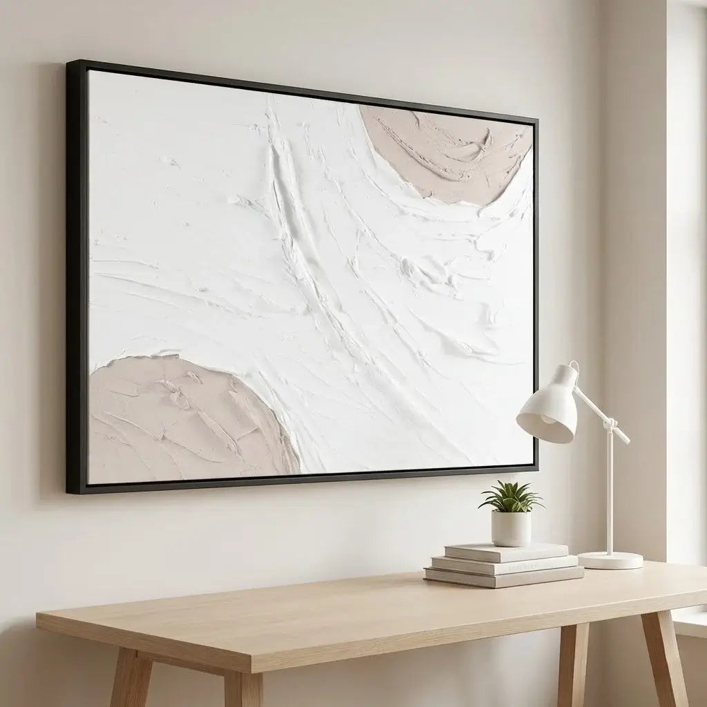 Abstract art piece on a wall above a wooden desk with a lamp and books.