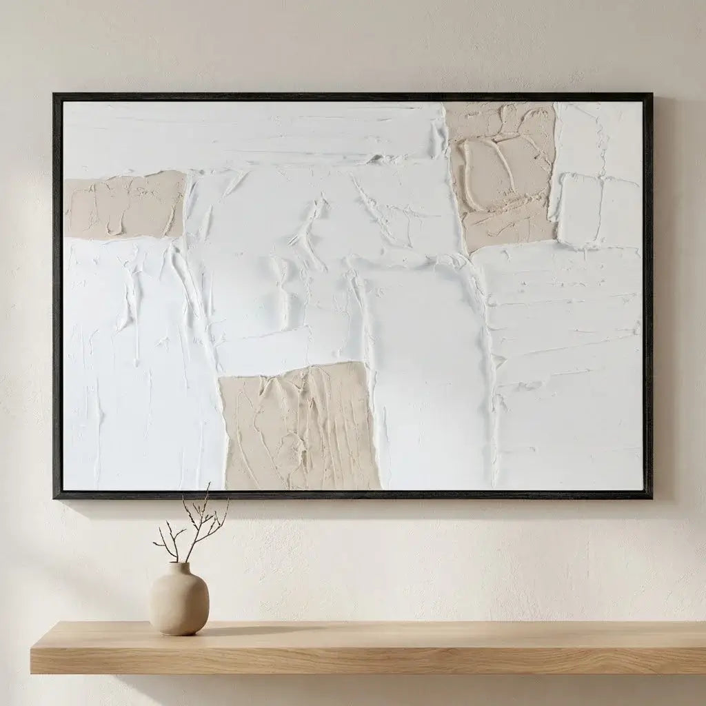 Abstract art piece in a black frame on a wall above a wooden shelf with a vase.