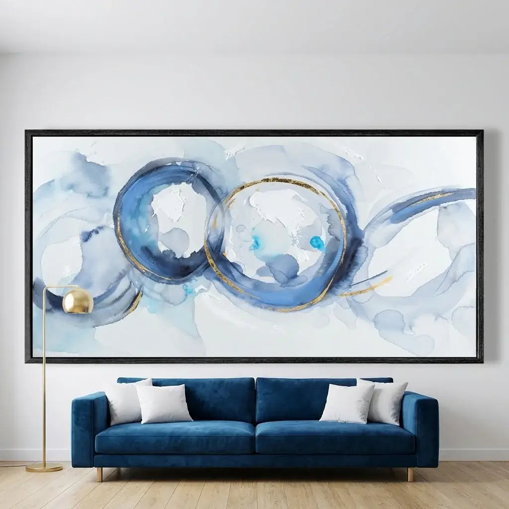 Abstract art piece with blue and white circles on a wall above a blue sofa.