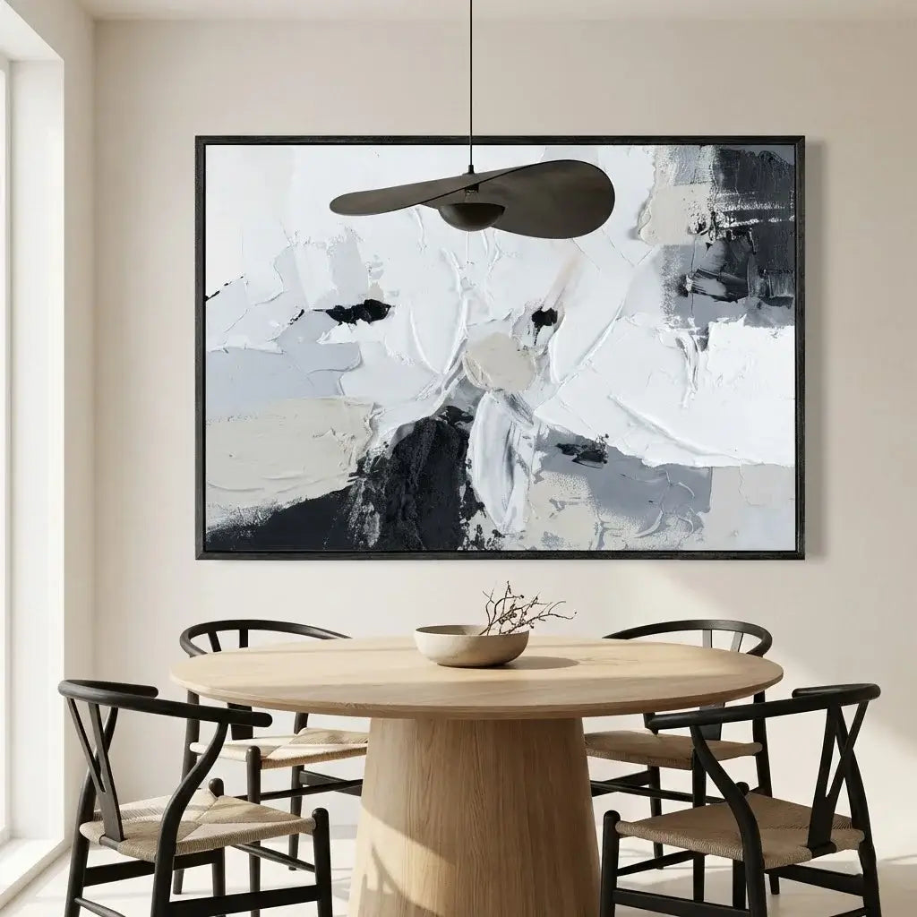 Dining room with a round wooden table and black chairs, abstract art on the wall.