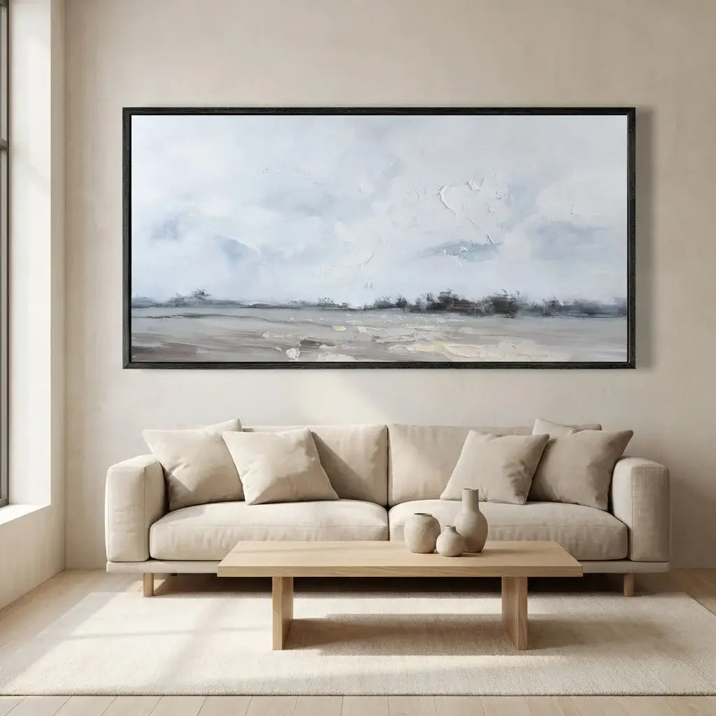 Framed landscape painting above a beige sofa in a living room.
