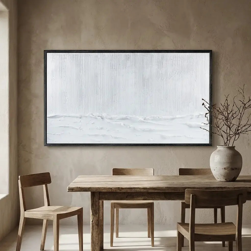 Dining room with wooden table and chairs, framed abstract art on the wall, and a vase with branches.