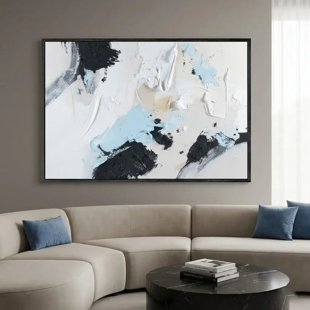 Abstract painting on a wall above a beige sofa with blue pillows.