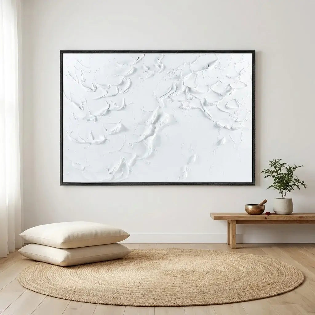 Abstract white artwork on a wall with a wooden bench, pillows, and a plant in a minimalistic room.