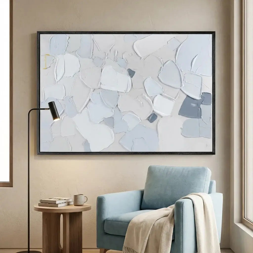Abstract art piece on a wall above a blue armchair in a living room.
