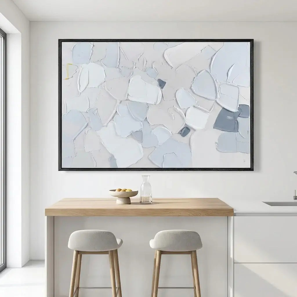 Abstract art piece on a wall above a kitchen island with stools.