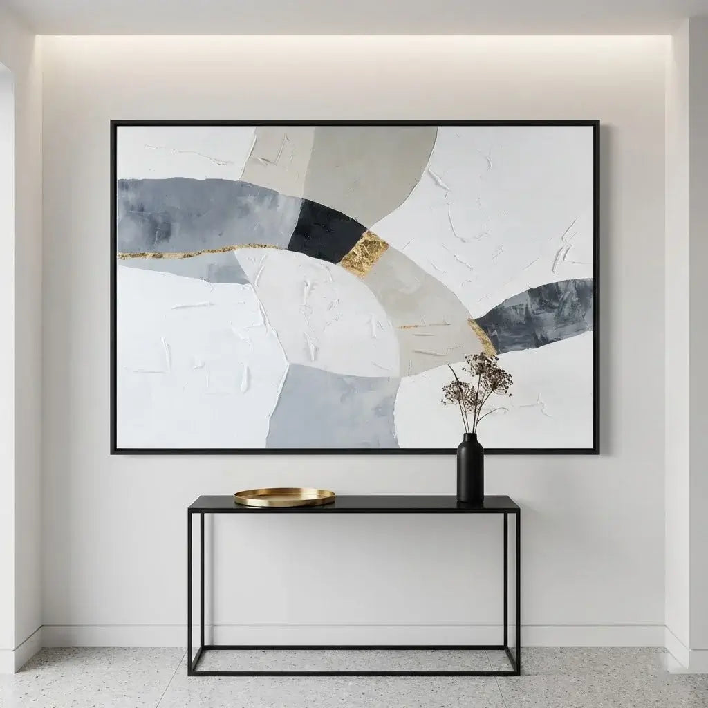 Abstract art piece on a wall above a black console table with a vase.