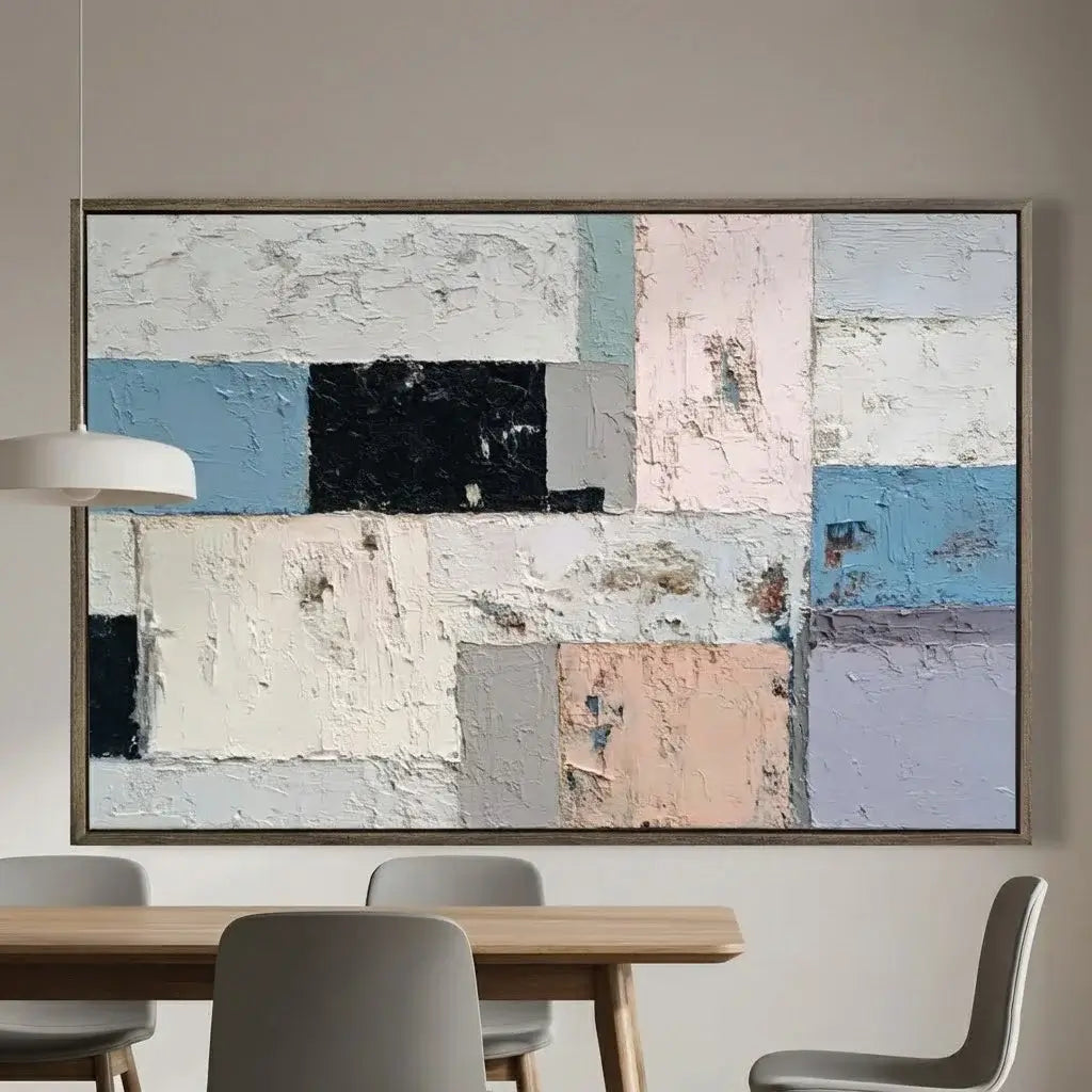 Abstract art piece on a wall above a dining table with chairs.