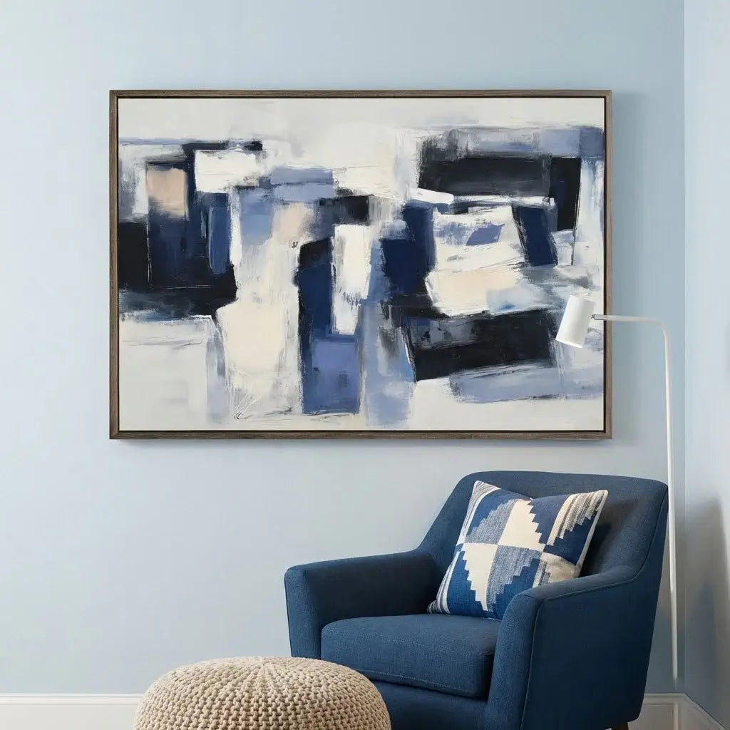 Abstract painting on a wall above a blue armchair with a patterned pillow.