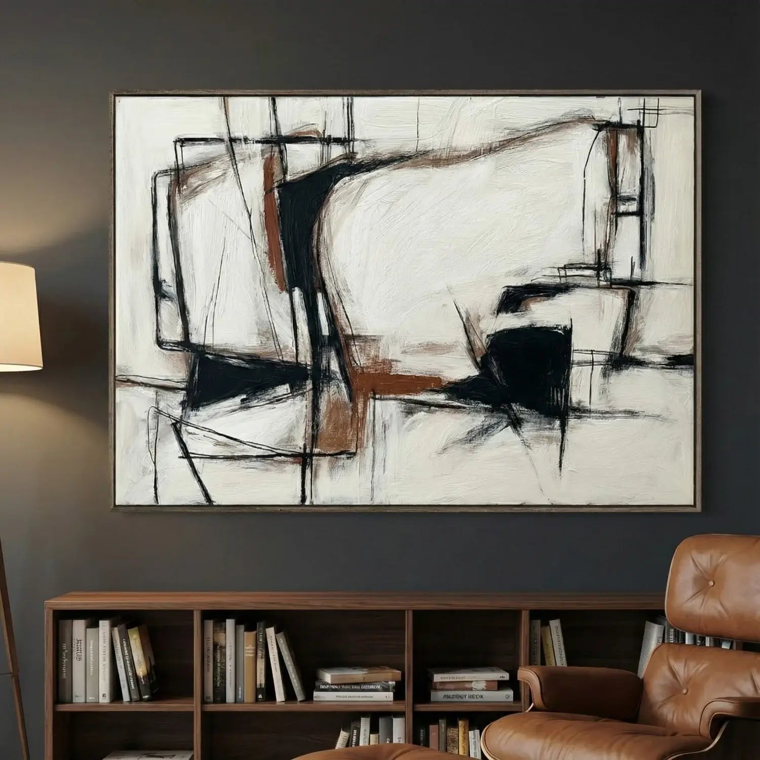 Abstract painting on a wall above a bookshelf and brown chair.
