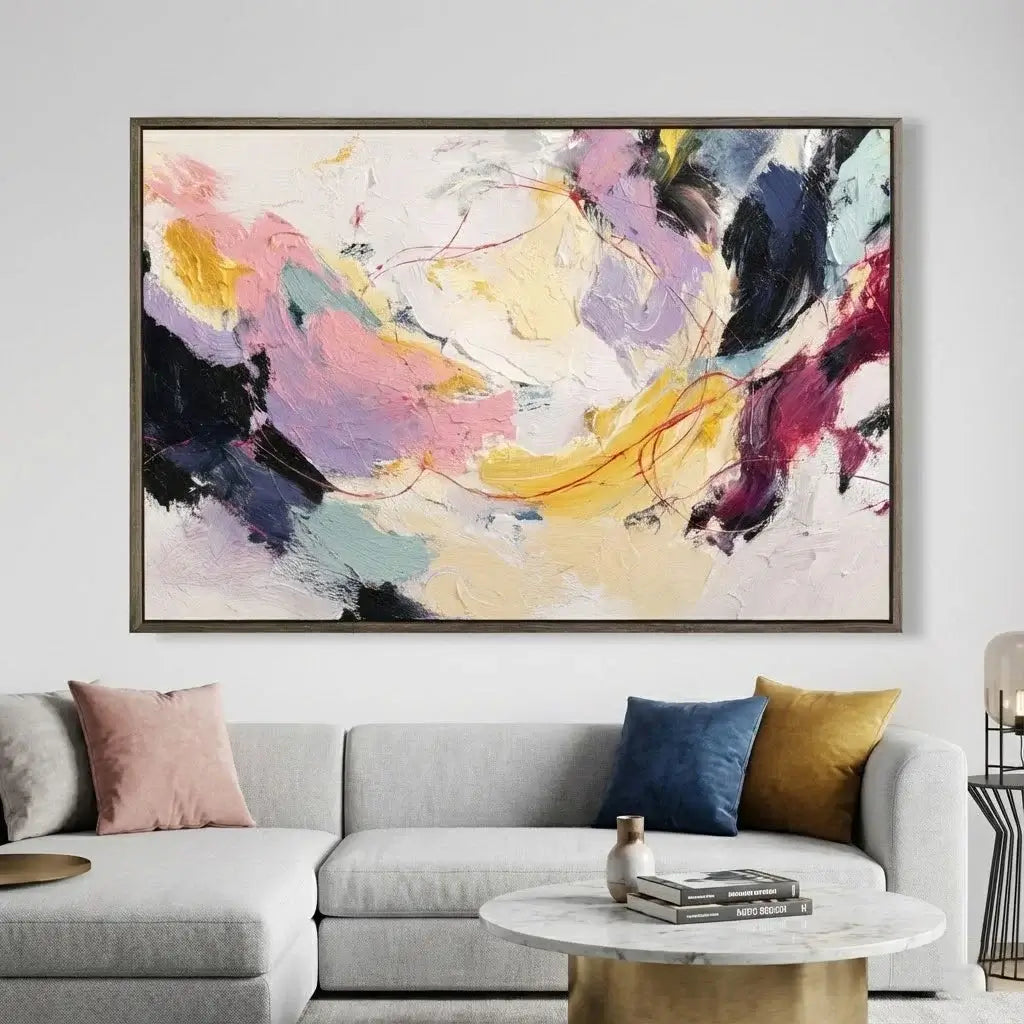 Abstract painting on a wall above a gray sofa with colorful cushions.