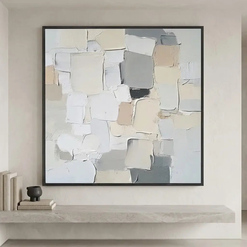 Abstract art piece with geometric shapes in neutral colors on a wall above a shelf.