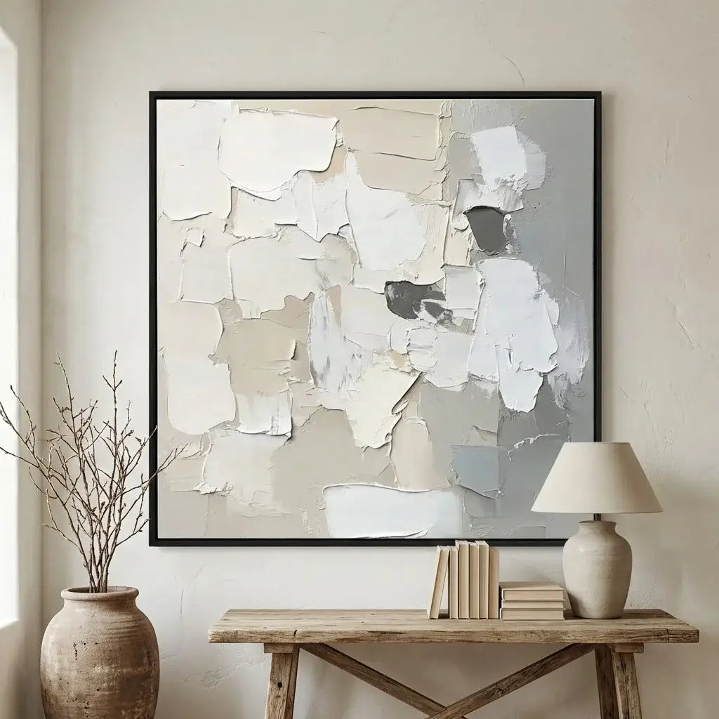 Abstract art piece in a black frame on a wall above a wooden console table with decor items.