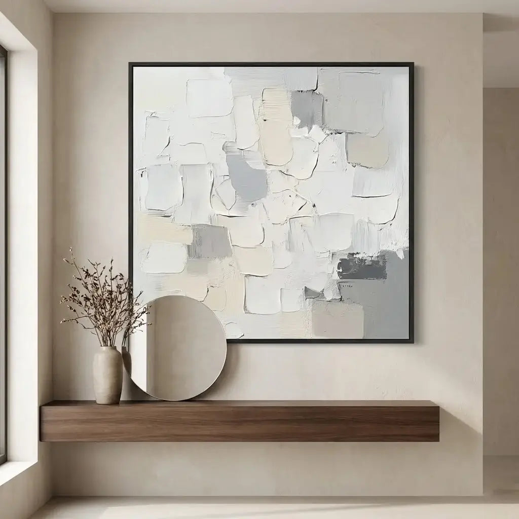 Abstract art piece on a wall above a wooden shelf with a vase and mirror.