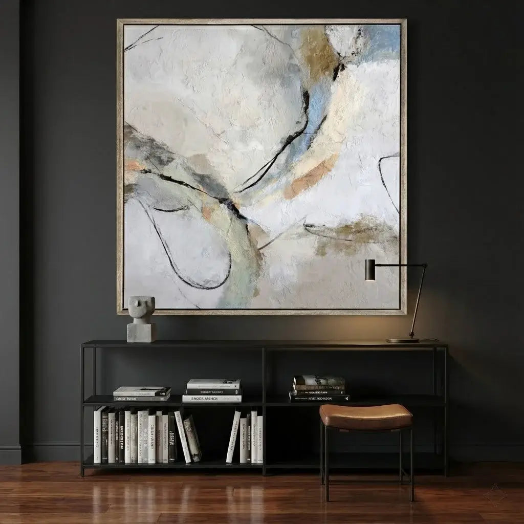 Abstract art piece on a dark wall above a shelf with books and decor.