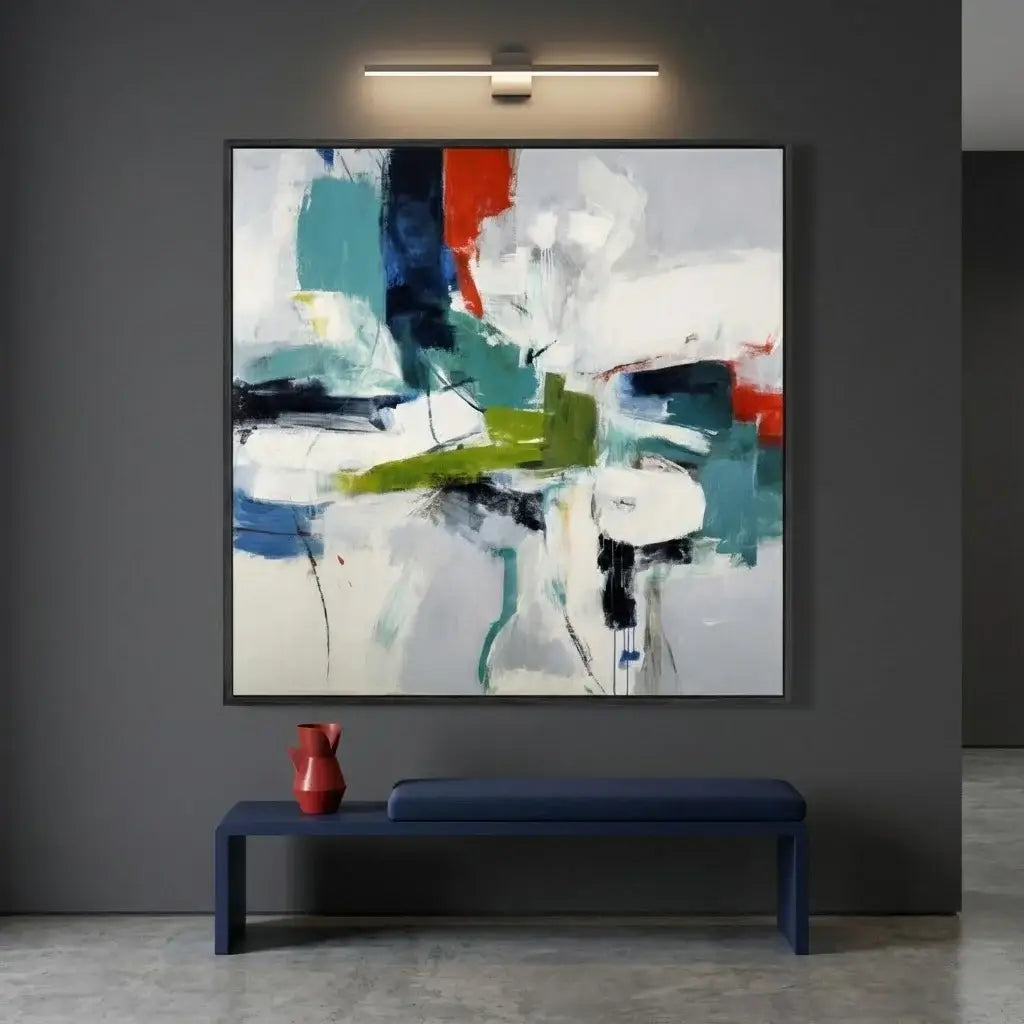 Abstract painting on a gray wall above a blue bench with a red vase.