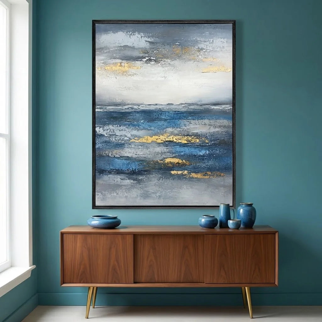 Abstract painting on a teal wall above a wooden cabinet with decorative items.